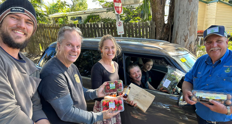 Producers handing their goods to Erica (sitting in car).