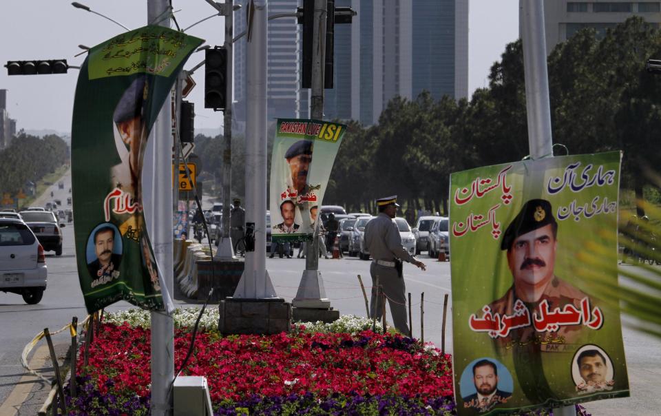 In this Saturday, April 26, 2014 file photo, banners showing pictures of Pakistan's Inter-Services Intelligence Chief Lt. General Zaheerul Islam, center, and army chief Gen. Raheel Sharif, right, are displayed by local traders in Islamabad, Pakistan. A controversy has started as Pakistan's powerful military faces off with the country’s largest private television station over allegations that its forces were behind a shooting that seriously wounded Hamid Mir, one of its top anchors. But behind the chanting demonstrations and garish loyalty posters lies the deep challenge confronting Pakistan: Where does power lie in this country that’s undergone three military coups since independence, with its army or its nascent civilian government? (AP Photo/Anjum Naveed, File)