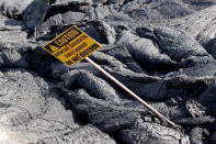 <p>A ‘Caution’ sign stands in a lava flow on the outskirts of Pahoa during ongoing eruptions of the Kilauea Volcano in Hawaii, June 6, 2018. (Photo: Terray Sylvester/Reuters) </p>