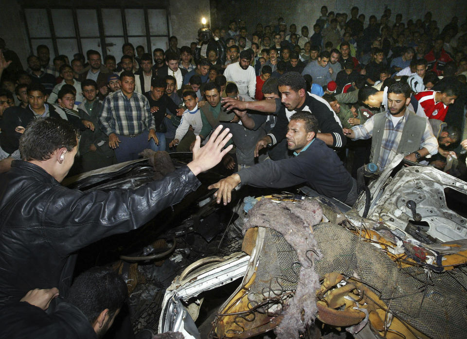 Palestinians chant and gather around the car of Hamas leader Abdel Aziz Rantisi, who was killed in an Israeli missile strike in Gaza City, Saturday, April 17, 2004. The benefits of such dramatic operations are symbolic achievement but often short-lived, bringing on further violence and equally formidable replacements as leaders of militant groups. (AP Photo/Kevin Frayer)