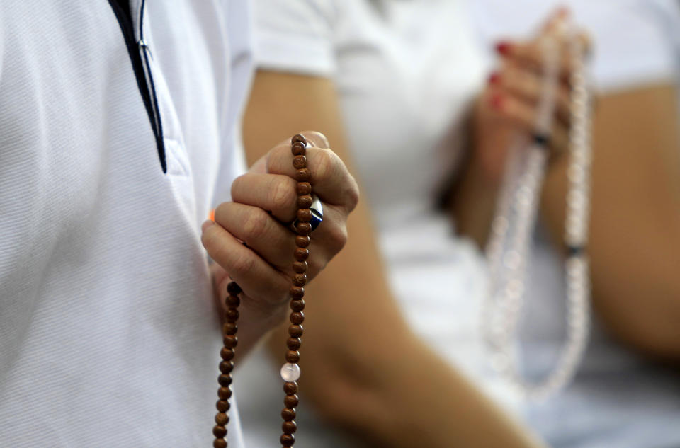 Buddhist devotees holding prayer beads offer prayers for passengers onboard the missing Malaysia Airlines Flight 370 at Kechara Forest Retreat in Bentong, outside Kuala Lumpur, Malaysia, Sunday, April 13, 2014. After a week of optimism over four underwater signals believed to be coming from the missing Malaysian plane, the sea has gone quiet and Australia's leader is warning that the massive search will likely be long. (AP Photo/Lai Seng Sin)