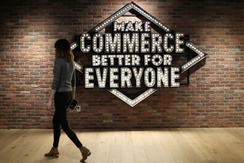 FILE PHOTO: An employee walks past a sign at Shopify's headquarters in Ottawa