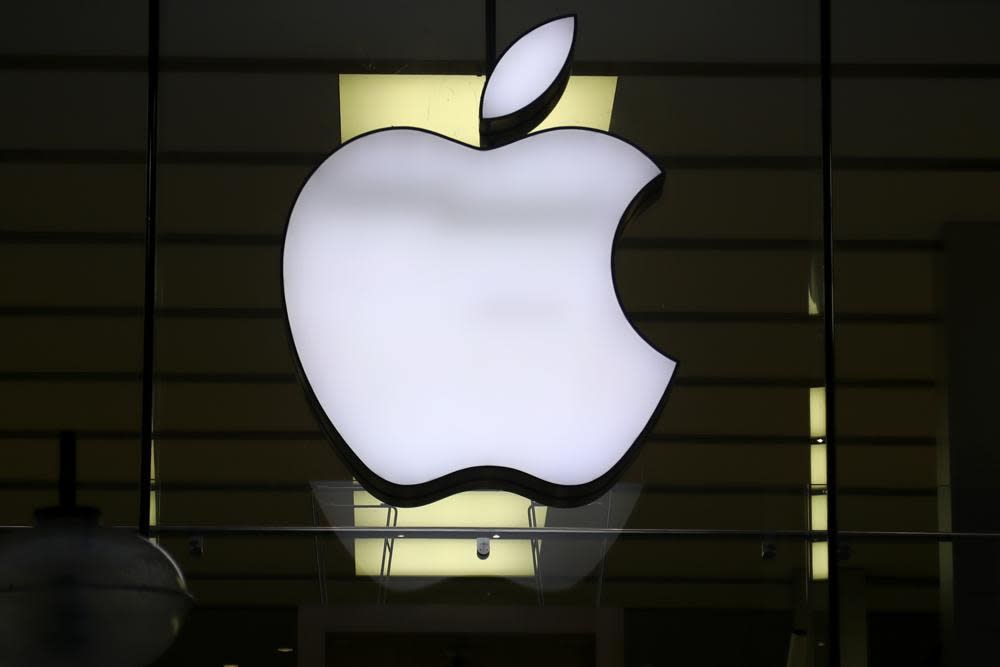 In this Wednesday, Dec. 16, 2020 file photo, the logo of Apple is illuminated at a store in the city center in Munich, Germany. (AP Photo/Matthias Schrader, file)
