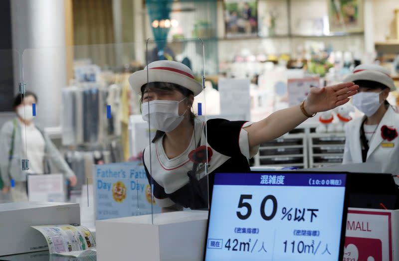 FILE PHOTO: A staff at an information desk talks to a customer through a transparent plastic panel at Japan's supermarket group Aeon's shopping mall as the mall reopens amid the coronavirus disease (COVID-19) outbreak in Chiba