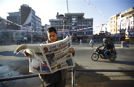 A Nepalese man reads a newspaper along a road a day after the Constituent Assembly election in Kathmandu November 20, 2013. Millions of Nepalis voted on Tuesday for an assembly that will draft a constitution aimed at ending years of instability but their ballots may not produce a conclusive result and could leave the country facing more turmoil. REUTERS/Navesh Chitrakar