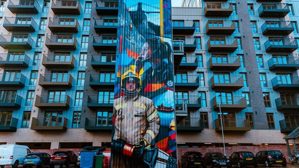 A giant mural painted on the side of the Avon Fire and Rescue building in Bristol showing a firefighter and a call handler