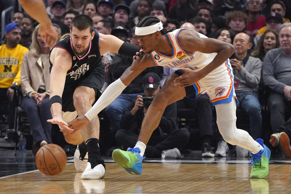 LA Clippers center Ivica Zubac, left, and Oklahoma City Thunder guard Shai Gilgeous-Alexander go after a loose ball during the first half of an NBA basketball game Thursday, March 23, 2023, in Los Angeles. (AP Photo/Mark J. Terrill)