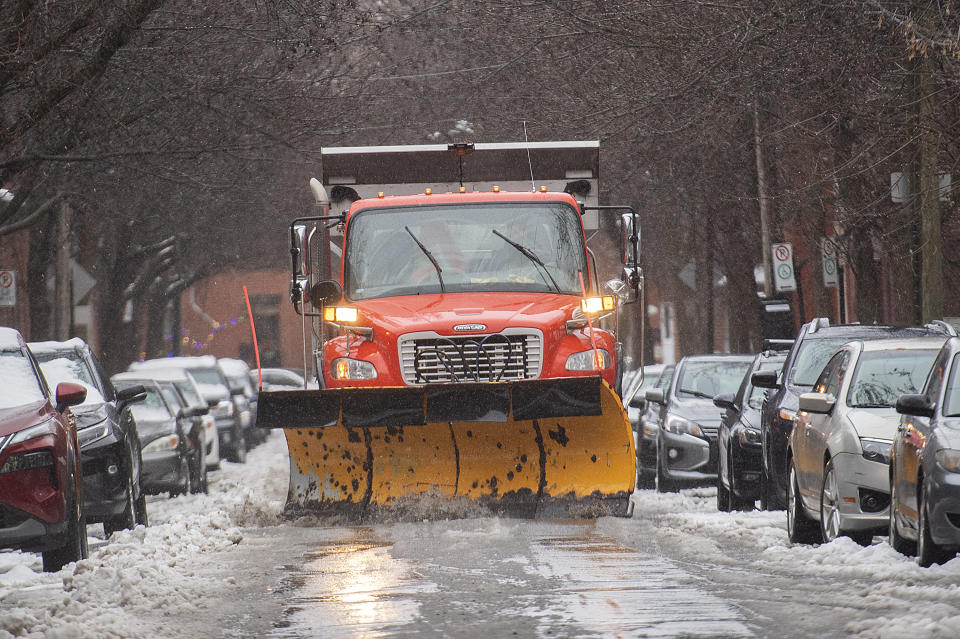 A plow clears water and slush from a street in Montreal, Friday, Dec. 23, 2022, as a storm system bears down on the region. (Graham Hughes/The Canadian Press via AP)