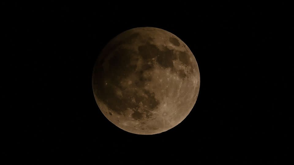 The moon looks a little darker during the 2023 penumbra lunar eclipse in Banda Aceh, Indonesia.  On Monday, the lunar event will begin at 12:53 PM ET.  -Chaideer Mahyuddin/AFP/Getty Images