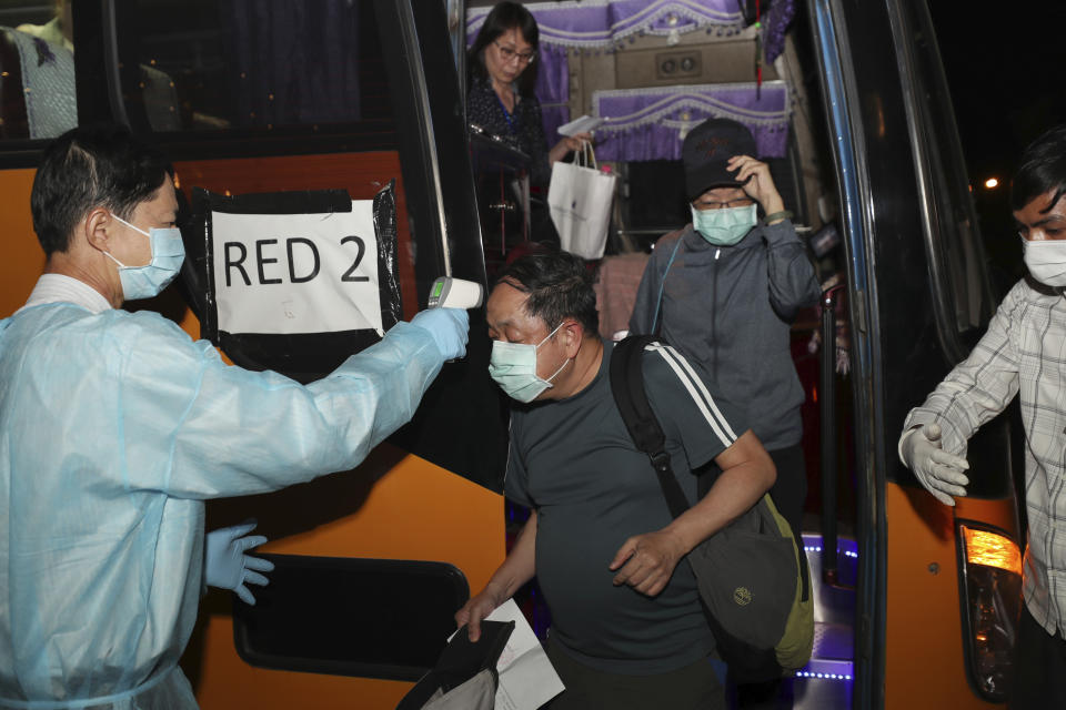 An unidentified passenger, left, from the MS Westerdam, owned by Holland America Line, receives temperature scanning during arrival in Phnom Penh, Cambodia, Wednesday, Feb. 19, 2020. Having finally reached a friendly port willing to accept them and stepped ashore after weeks of uncertainty at sea, some hundreds of the cruise ship passengers eyed warily over fears of a new virus are now finding a way home. (AP Photo/Heng Sinith)