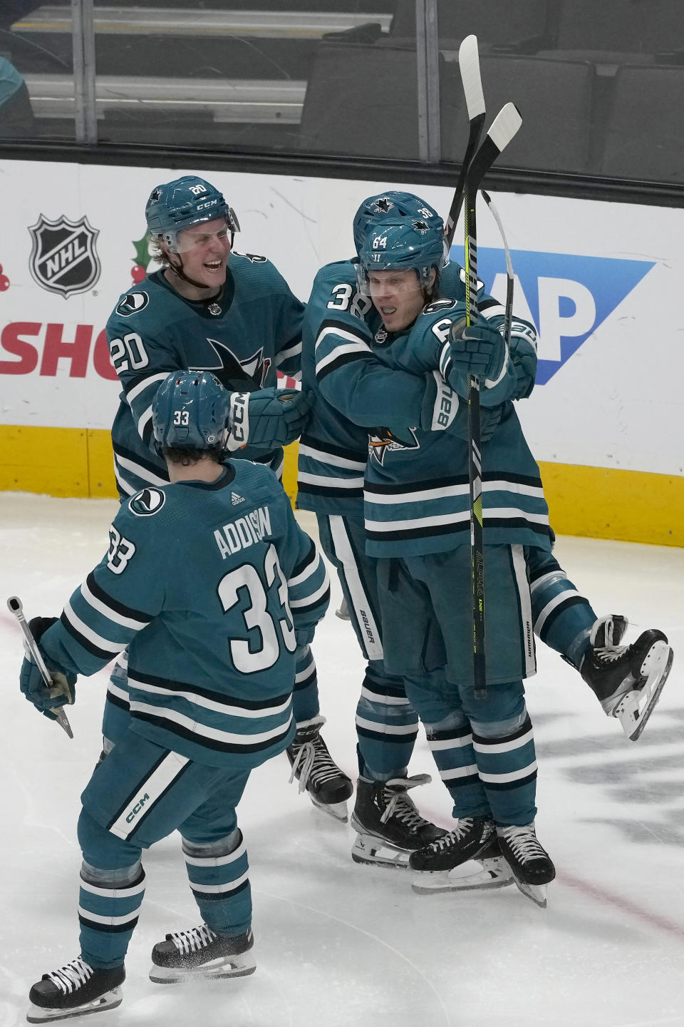 San Jose Sharks center Mikael Granlund (64) is congratulated by defenseman Mario Ferraro (38), left wing Fabian Zetterlund (20) and defenseman Calen Addison (33) after scoring against the Vancouver Canucks during the third period of an NHL hockey game in San Jose, Calif., Saturday, Nov. 25, 2023. (AP Photo/Jeff Chiu)