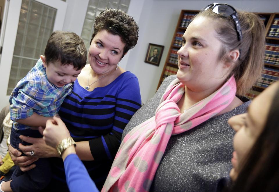 Nicole Yorksmith, left, holds her son while standing with her partner Pam Yorksmith, Monday, Feb. 10, 2014, following a news conference in Cincinnati. Four legally married gay couples filed a federal civil rights lawsuit Monday seeking a court order to force Ohio to recognize same-sex marriages on birth certificates despite a statewide ban. (AP Photo/Al Behrman)