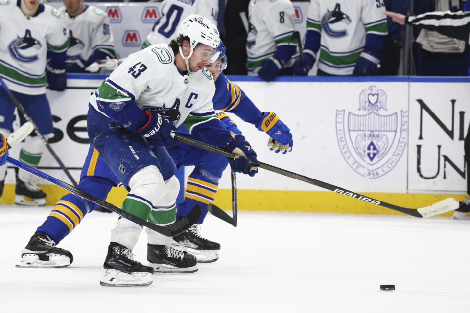 Vancouver Canucks defenseman Quinn Hughes (43) is pressured by Buffalo Sabres defenseman Owen Power, right, during the second period of an NHL hockey game Saturday, Jan. 13, 2024, in Buffalo, N.Y. (AP Photo/Jeffrey T. Barnes)