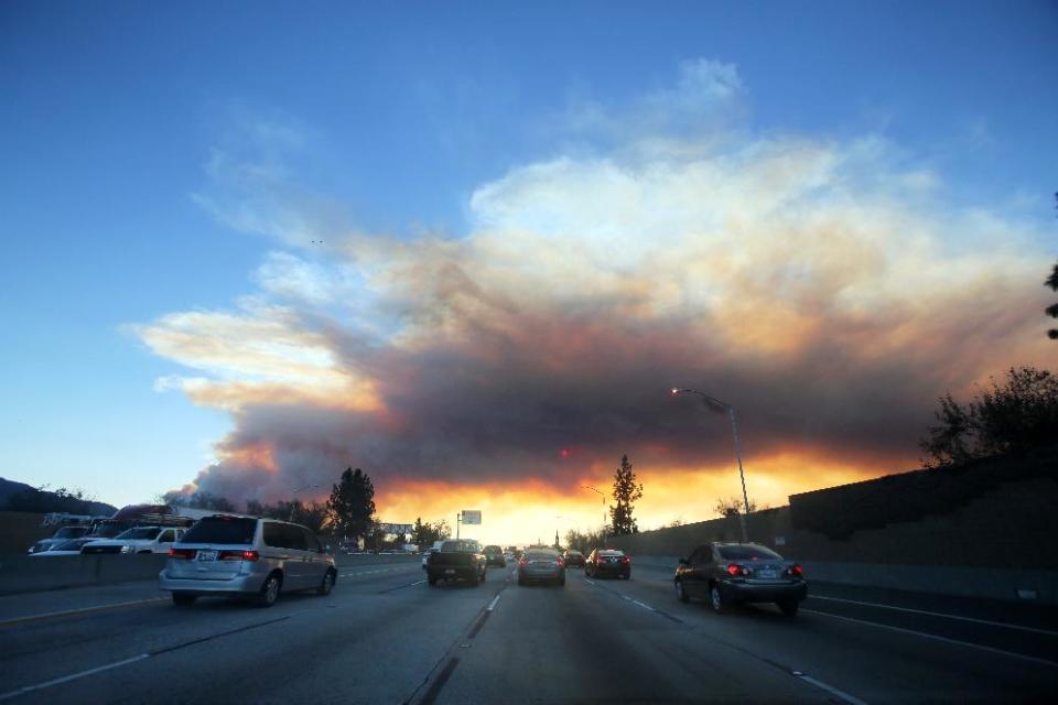 Commuters make their way along the 210 freeway as a wildfire burns in the hills just north of the San Gabriel Valley community of Glendora, Calif. on Thursday, Jan 16, 2014. Southern California authorities have ordered the evacuation of homes at the edge of a fast-moving wildfire burning in the dangerously dry foothills of the San Gabriel Mountains. (AP Photo/Ringo H.W. Chiu)