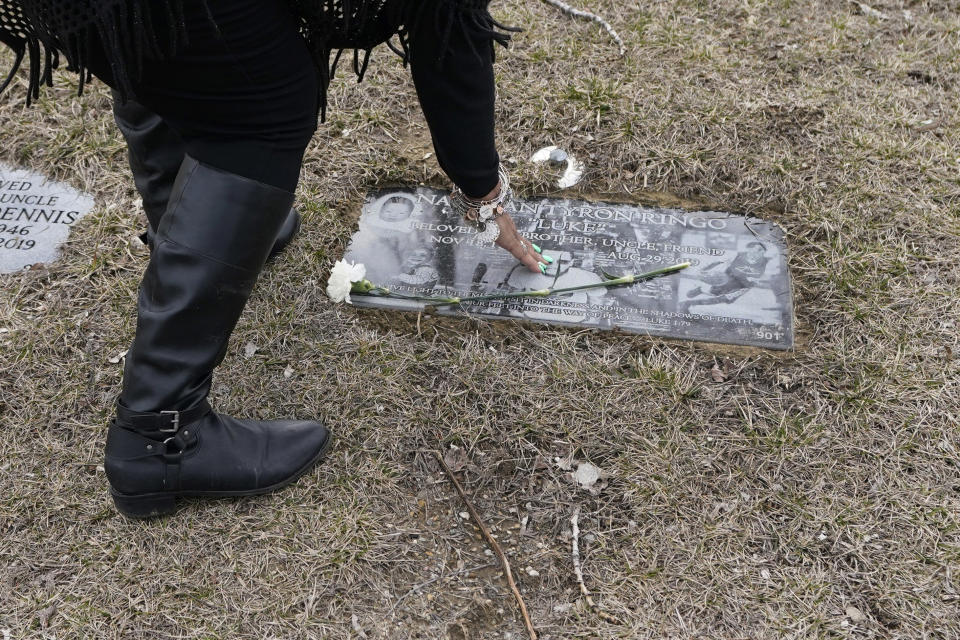 Bernice Ringo touches her son Natalian's grave marker, Tuesday, March 28, 2023, in Redford Charter Township, Mich. Natalian was fatally shot while sitting in his car in 2019. After being denied victim compensation and overwhelmed with grief, Ringo spoke to the Michigan Legislature about the trauma of being told her son had caused his murder. (AP Photo/Carlos Osorio)