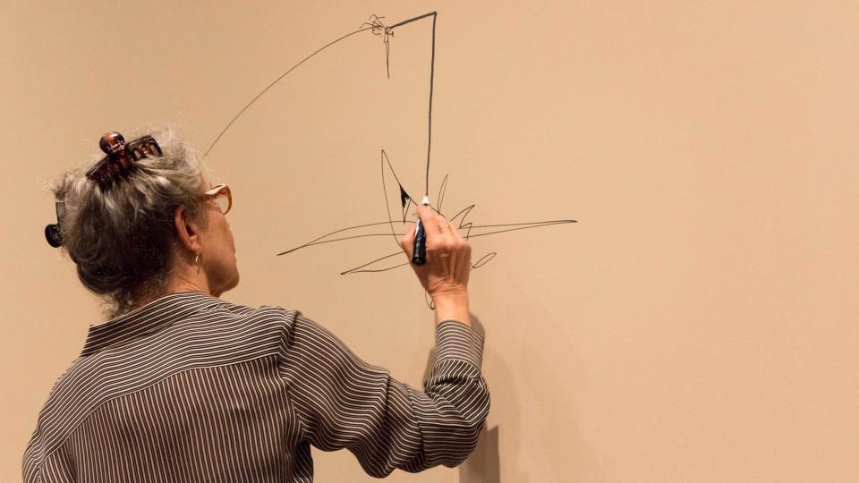 Deborah Hay makes a drawing on the wall of the resource room as part of the exhibit "Perception Unfolds: Looking at Deborah Hays Dance" at the Blanton Museum of Art in 2014. These kinds of drawings fill her "scores," which inform the dances she makes.