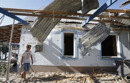 A man walks past a house damaged by recent shelling on the outskirts of the southern coastal town of Mariupol September 7, 2014. REUTERS/Vasily Fedosenko