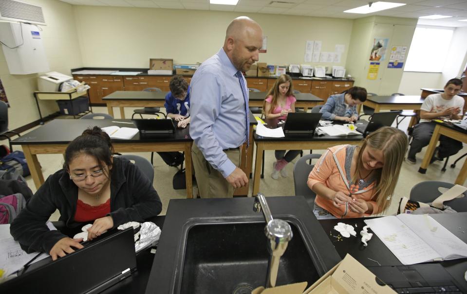 Beech Grove High School teacher Chris Kaufman watches as Rebecca Goodman, right, makes a flower out of clay during a Plant and Soil Science class Wednesday, April 30, 2014, in Indianapolis. High school agriculture programs sprouting across the nation’s Corn Belt are teaching teenagers, many of them in urban environments, that careers in the field often have nothing to do with cows and plows. (AP Photo/Darron Cummings)