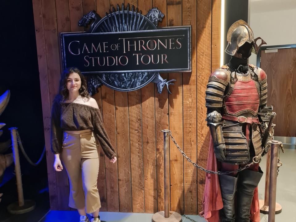 Eibhlis Gale-Coleman posing next to a suit of armor at the entrance to the game of thrones studio tour