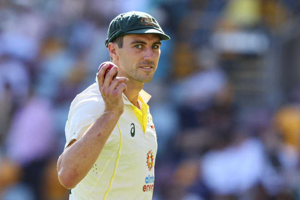 Australia's Pat Cummins holds the ball up to the crowd after taking five wickets during day two of the first cricket test between South Africa and Australia at the Gabba in Brisbane, Australia, Sunday, Dec.18, 2022. (AP Photo/Tertius Pickard)