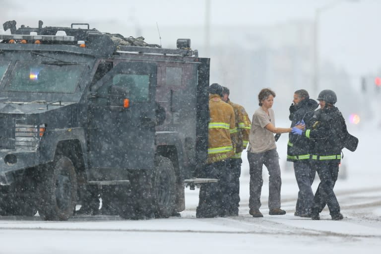 A woman is escorted from a police vehicle after being rescued when a gunman opened fire at a family planning center in Colorado in a standoff that dragged on for five hours before he surrendered