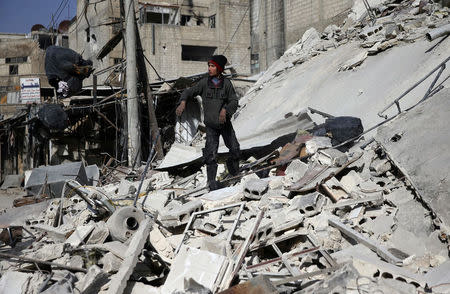 A boy stands on the rubble of a damaged building at the besieged town of Douma, Eastern Ghouta, Damascus, Syria March 5, 2018. REUTERS/Bassam Khabieh