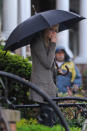 Con look casual, apenas abrigada, Emma Stone combate a la lluvia apenas cubierta por un gran paraguas negro. Sobriedad.