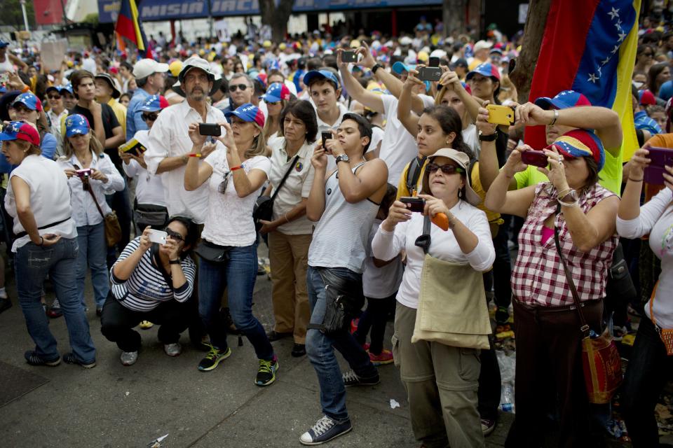 Demonstrators take pictures of a performance at an anti-government protest in Caracas, Venezuela, Sunday, March 2, 2014. Since mid-February, anti-government activists have been protesting high inflation, shortages of food stuffs and medicine, and violent crime in a nation with the world's largest proven oil reserves. (AP Photo/Rodrigo Abd)