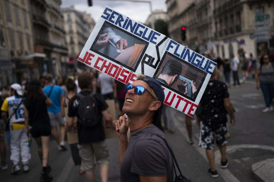 FILE - A protester marches with a sign reading in French "syringe or gun" during an anti-lockdown demonstration in Marseille, southern France, Aug. 7, 2021. The pandemic is again roaring across parts of Western Europe, a prosperous region with relatively high vaccination rates and good health care systems but where lockdown measures to rein in the virus are largely a thing of the past. France, also in the midst of a rise in infections, is pinning its hopes on booster shots for people already fully vaccinated while urging holdouts to get their shots. (AP Photo/Daniel Cole, file)