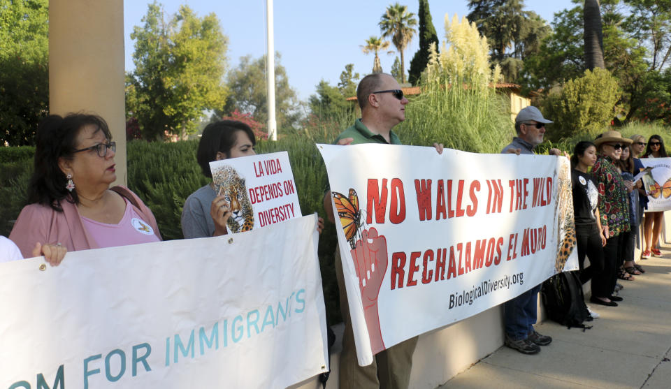 Members of the Center for Biological Diversity and other immigrant advocates protest outside 9th U.S. Circuit Court of Appeals court hearing challenging Trump's border wall Tuesday, Aug. 7, 2018, in Pasadena, Calif. A federal appeals court will hear arguments by the state of California that the Trump administration overreached by waiving environmental reviews to speed construction of the president's prized border wall with Mexico. At issue Tuesday before a three-judge panel in Pasadena, California, is a 2005 law that gave the Homeland Security secretary broad authority to waive dozens of laws including the National Environmental Policy Act and Endangered Species Act. (AP Photo/Ariel Tu)