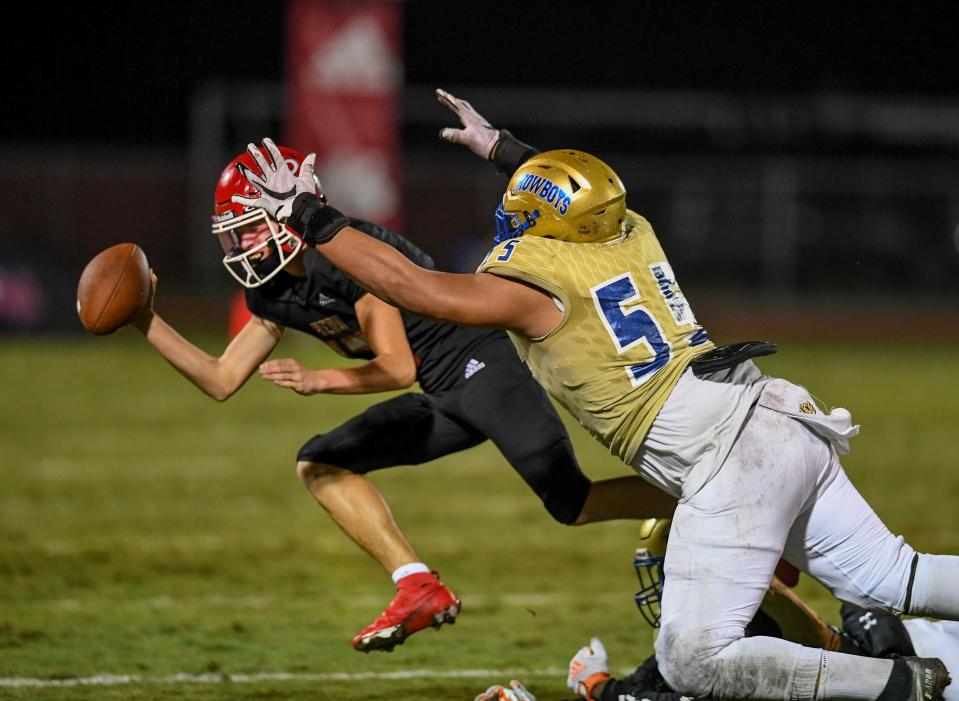 John Walker, (right) of the Osceola Kowboys, leaps after Vero Beach quarterback Jake Whiteley as Whiteley sends the ball into the sidelines in the 4th quarter of their FHSAA Regional Final Playoff game at the Vero Beach High School Citrus Bowl on Friday, Nov. 25, 2022, in Vero Beach. Osceola won against Vero Beach 31-7.