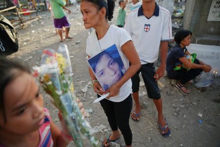 The mother of Angelo Lafuente, whose body, riddled with bullets, was found by a filthy river that feeds into the Manila bay, holds his picture as she visits his grave on the All Saints Day in Manila, Philippines November1, 2016. REUTERS/Damir Sagolj