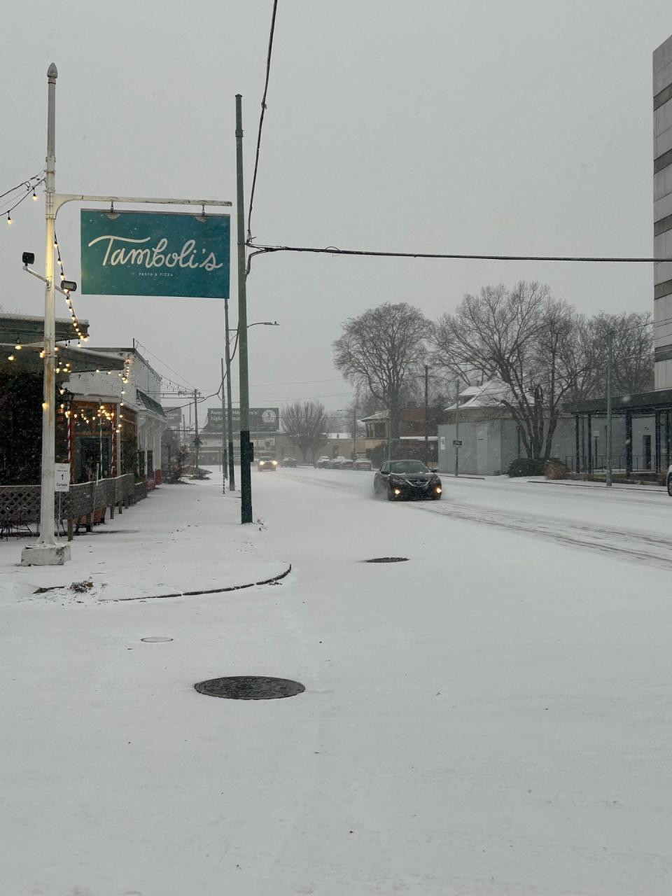 A car is seen driving down Madison Avenue as snow falls in Memphis on Sunday, Jan. 14, 2024. The Memphis area is expecting 3 to 6 inches of snow and below-freezing temperatures.