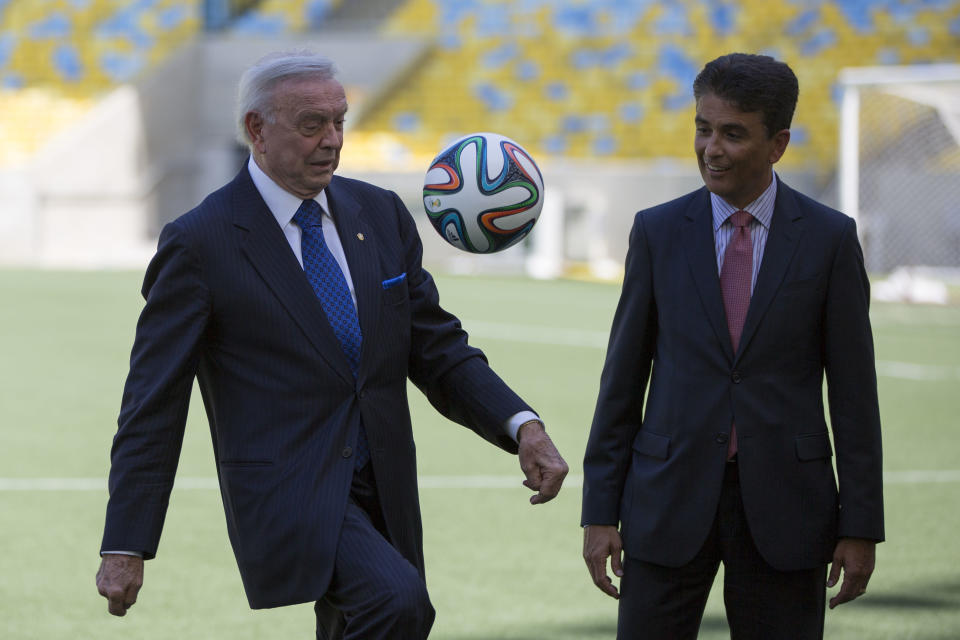 President of the local organizing committee for the 2014 World Cup Jose Maria Marin, left, plays with a soccer ball as former Brazilian soccer star Bebeto looks on, after a news conference to announce the 2014 World Cup song at the Maracana stadium in Rio de Janeiro, Brazil, Thursday, Jan. 23, 2014. FIFA says Jennifer Lopez will team up with rapper Pitbull and popular Brazilian singer Claudia Leitte to perform the official song of the World Cup. (AP Photo/Felipe Dana)