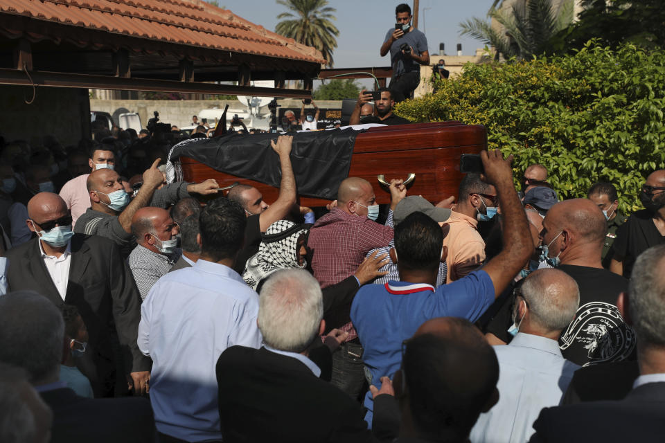 Mourners carry the body Saeb Erekat into the family house during his funeral in the West Bank city of Jericho, Wednesday, Nov. 11, 2020. Erekat, a veteran peace negotiator and prominent international spokesman for the Palestinians for more than three decades, died on Tuesday, weeks after being infected by the coronavirus. He was 65. (AP Photo/Nasser Nasser)