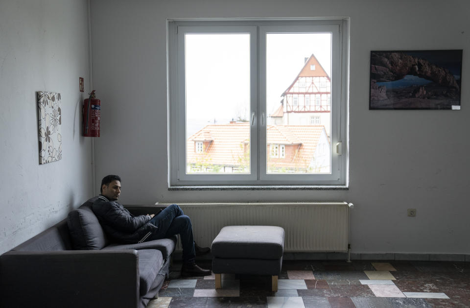 An asylum seeker man is sitting in a corner of a refugee shelter, in Eichsfeld, Germany, Wednesday, April 24, 2024. Across Germany, cities and counties are introducing new payment cards for asylum-seekers. The new rule, which was passed by parliament last month, calls for the migrants to receive their benefits on a card that can be used for payments in local shops and services. (AP Photo/Ebrahim Noroozi)