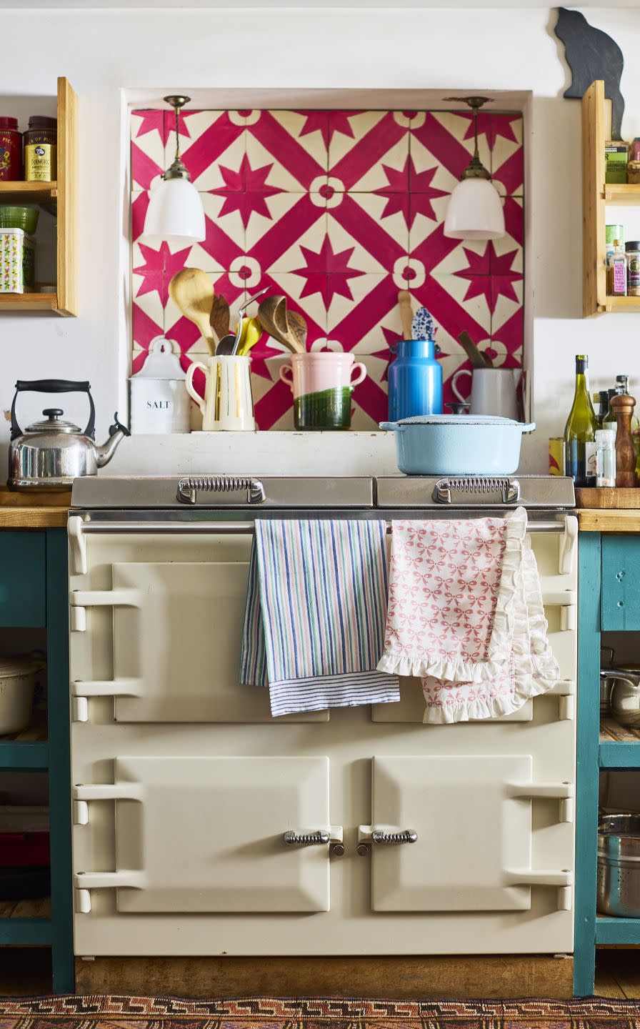 a quirky kitchen with cream aga and pink patterned tiles