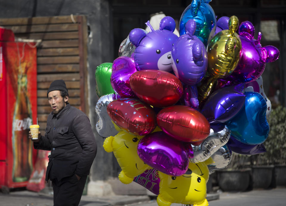 A chinese balloon vendor waiting for costumer in downtown Beijing, China, Friday, March 7, 2014. China today expressed confidence over achieving its GDP target of 7.5 per cent this year, citing the expected recovery of the world economy and strong fundamentals of emerging markets. (AP Photo/Vincent Thian)