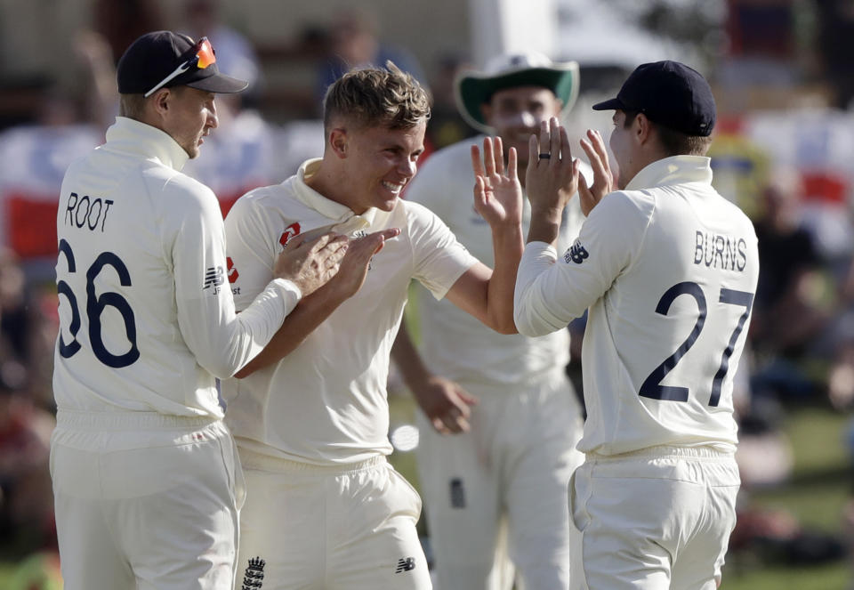 England's Sam Curran, centre, is congratulated by teammates, Joe Root, left, and Rory Burns after dismissing New Zealand's Kane Williamson during play on day two of the first cricket test between England and New Zealand at Bay Oval in Mount Maunganui, New Zealand, Friday, Nov. 22, 2019. (AP Photo/Mark Baker)