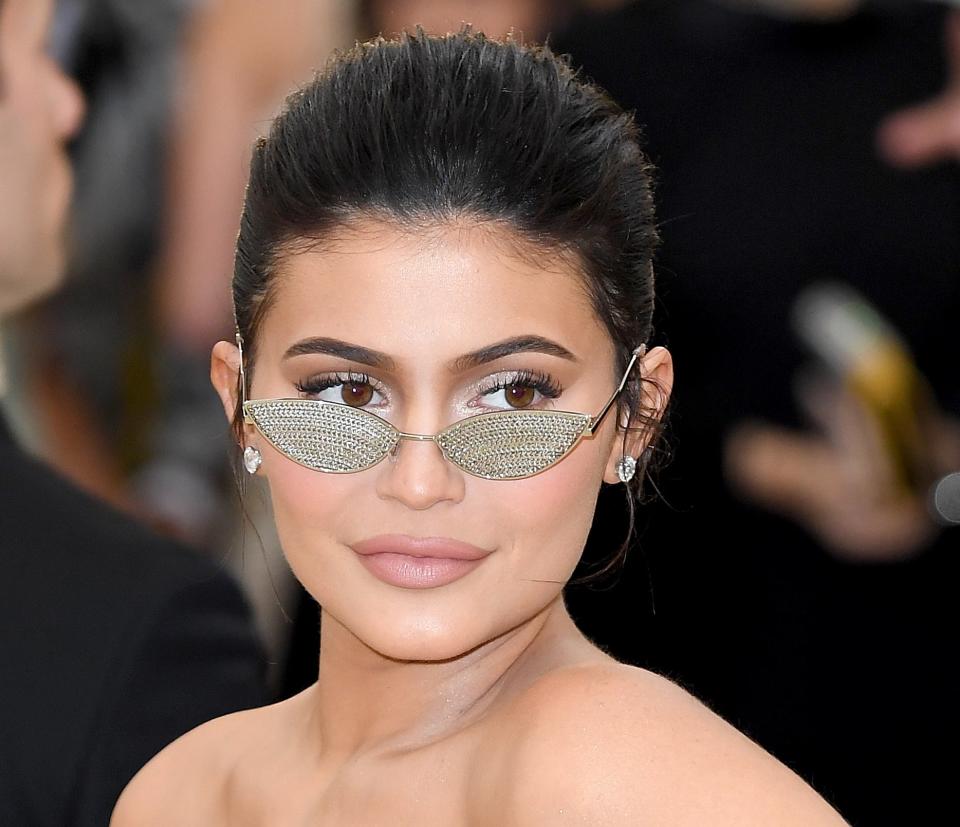 Kylie Jenner poses at an event in a cut-out dress with unique sunglasses