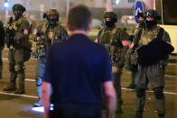 A protester stands in front of armed police during a mass protest following presidential elections in Minsk, Belarus, Monday, Aug. 10, 2020. Thousands of people have protested in Belarus for a second straight night after official results from weekend elections gave an overwhelming victory to authoritarian President Alexander Lukashenko, extending his 26-year rule. A heavy police contingent blocked central squares and avenues, moving quickly to disperse protesters and detained dozens. (AP Photo/Sergei Grits)