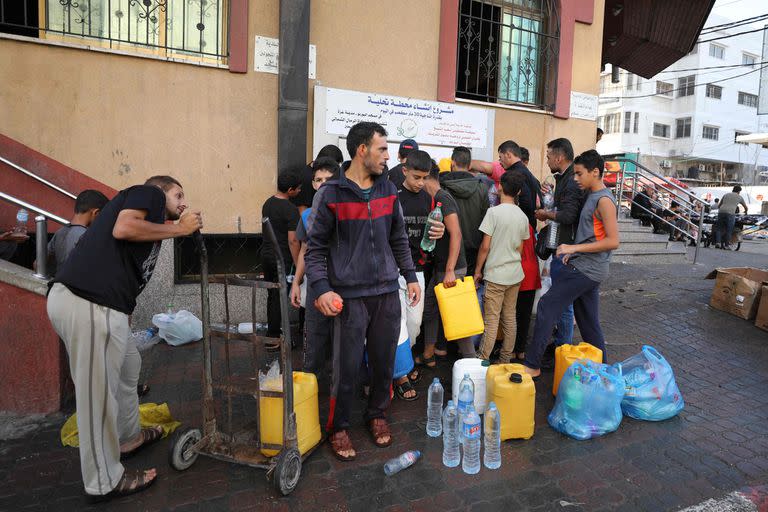 Palestinos hacen cola para llenar cantimploras de agua en la ciudad de Gaza, el 16 de octubre de 2023.