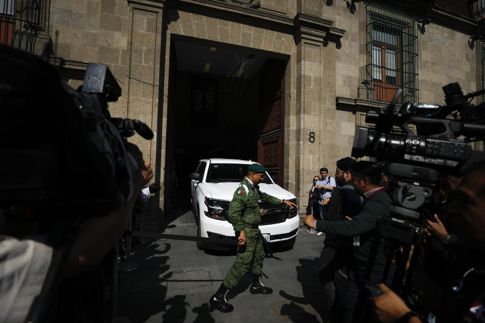 Journalists film as a vehicle carrying a Mexican official leaves the National Palace following a private meeting between U.S. Attorney General William Barr and Mexico's President Andres Manuel Lopez Obrador, in Mexico City, Thursday, Dec. 5, 2019. (AP Photo/Rebecca Blackwell)