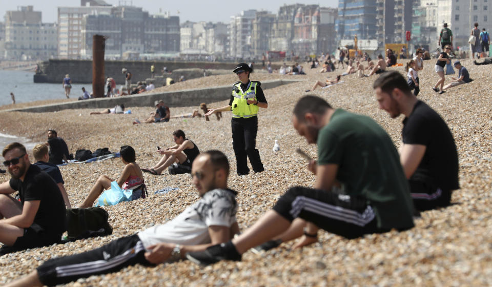 A police officer advises a group of people to move from Brighton Beach in East Sussex, England as the UK continues in lockdown to help curb the spread of the coronavirus, Saturday May 9, 2020. (Gareth Fuller/PA via AP)