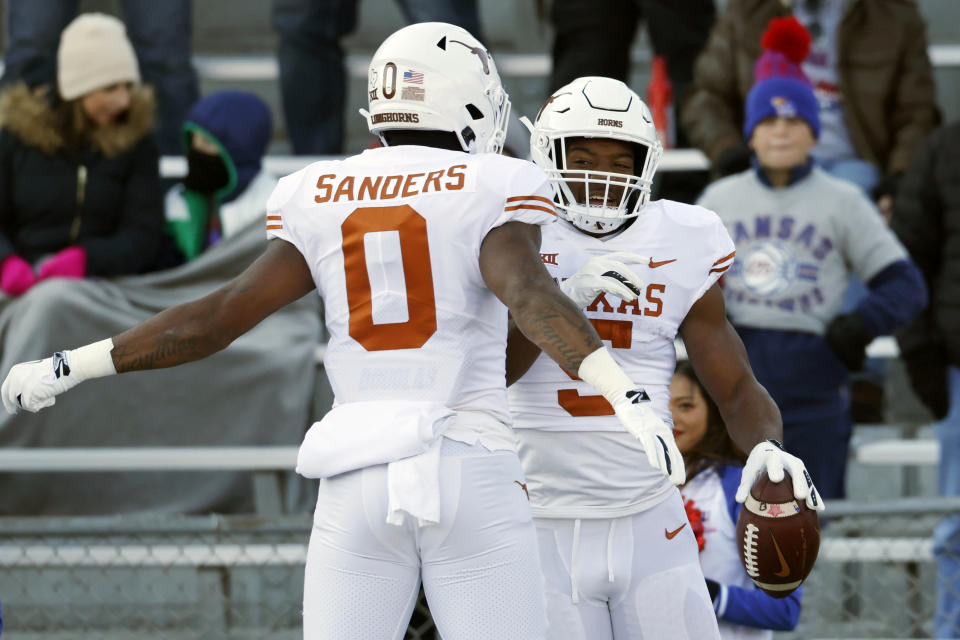 Texas running back Bijan Robinson (5) celebrates with tight end Ja'Tavion Sanders (0) after scoring a touchdown during the first quarter of an NCAA college football game against Kansas, Saturday, Nov. 19, 2022, in Lawrence, Kan. (AP Photo/Colin E. Braley)