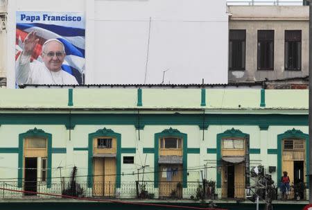 A woman stands on a balcony near a photograph of Pope Francis in downtown Havana, September 17, 2015. REUTERS/Stringer