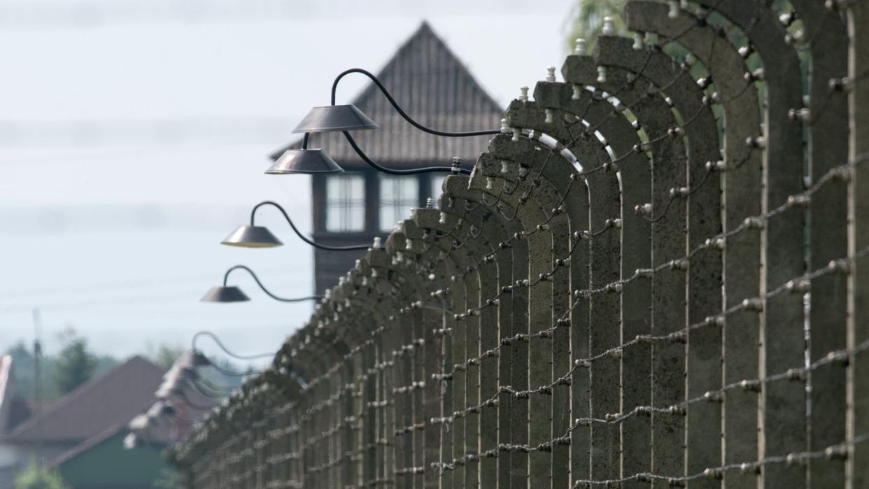 Stacheldrahtzäune und ein Wachturm auf dem Gelände des ehemaligen Vernichtungslagers Auschwitz-Birkenau.