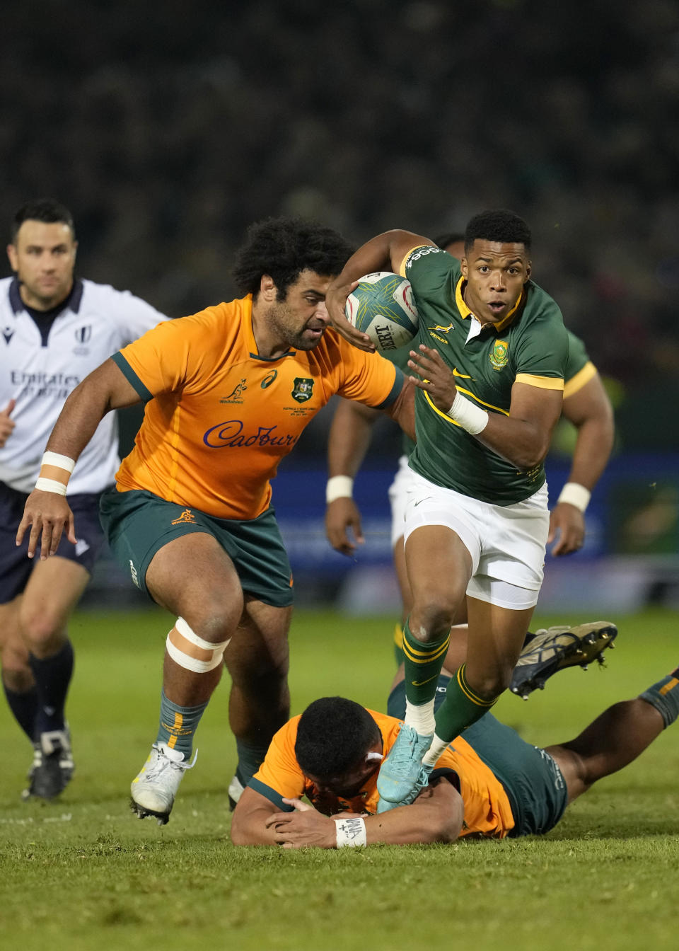 South Africa's Grant Williams, front, jumps as he avoids a tackle from Australia's Jordan Uelese, bottom, during the Rugby Championship test match between South Africa and Australia at Loftus Versfeld stadium in Pretoria, South Africa, Saturday, July 8, 2023. (AP Photo/Themba Hadebe)