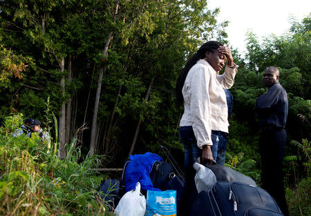 A family that stated they are from Haiti waits to enter into Canada from Roxham Road in Champlain, New York, U.S. August 11, 2017. REUTERS/Christinne Muschi