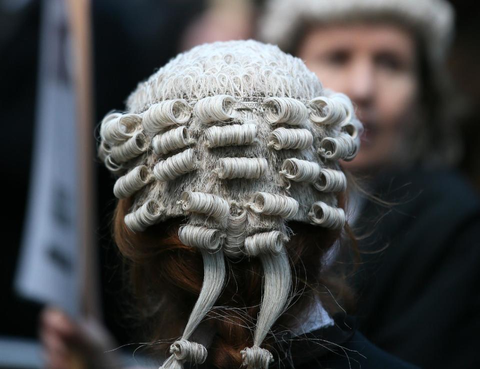 Lawyer Alice Jarratt takes part in a protest outside Southwark Crown Court during a demonstration against cuts to legal aid funding, in London, Monday, Jan. 6, 2014. Hundreds of British lawyers, many dressed in traditional wigs and gowns, have swapped courtrooms for picket lines to protest planned cuts to legal-aid funding. Hearings were disrupted Monday at courts including London’s famous Old Bailey as barristers staged their first-ever national walkout. The British government, which has slashed spending in the name of deficit reduction, plans to cut lawyers’ fees in a bid to reduce the legal aid budget by 220 million pounds ($360 million) by 2019. (AP Photo/Alastair Grant)